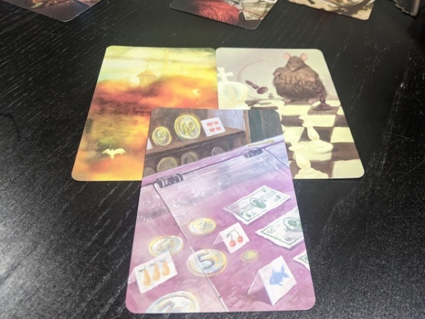 Three Mysterium vision cards, one showing a rat playing chess, the second showing trinkets behind glass like in a jewelry store, and one showing a castle in fog.