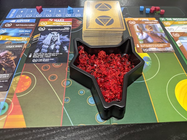 In the middle of a game of Red Rising, the board shows four columns (locations) with cards stacked in each. Front and centre is the container of Helium tokens.