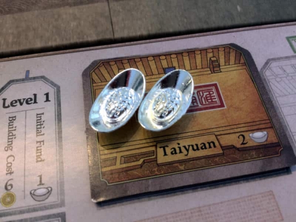 Two little silver ingots, the sycee, on a thick, cardboard branch tile