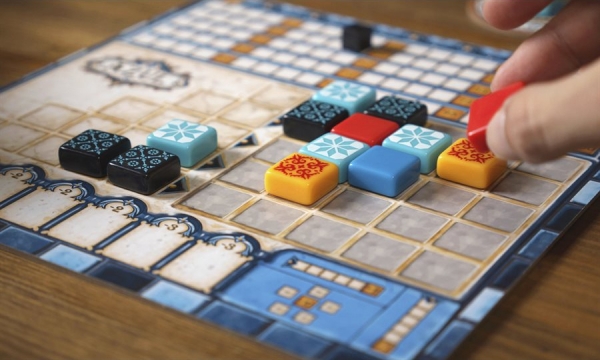 A hand places tiles on the Azul board